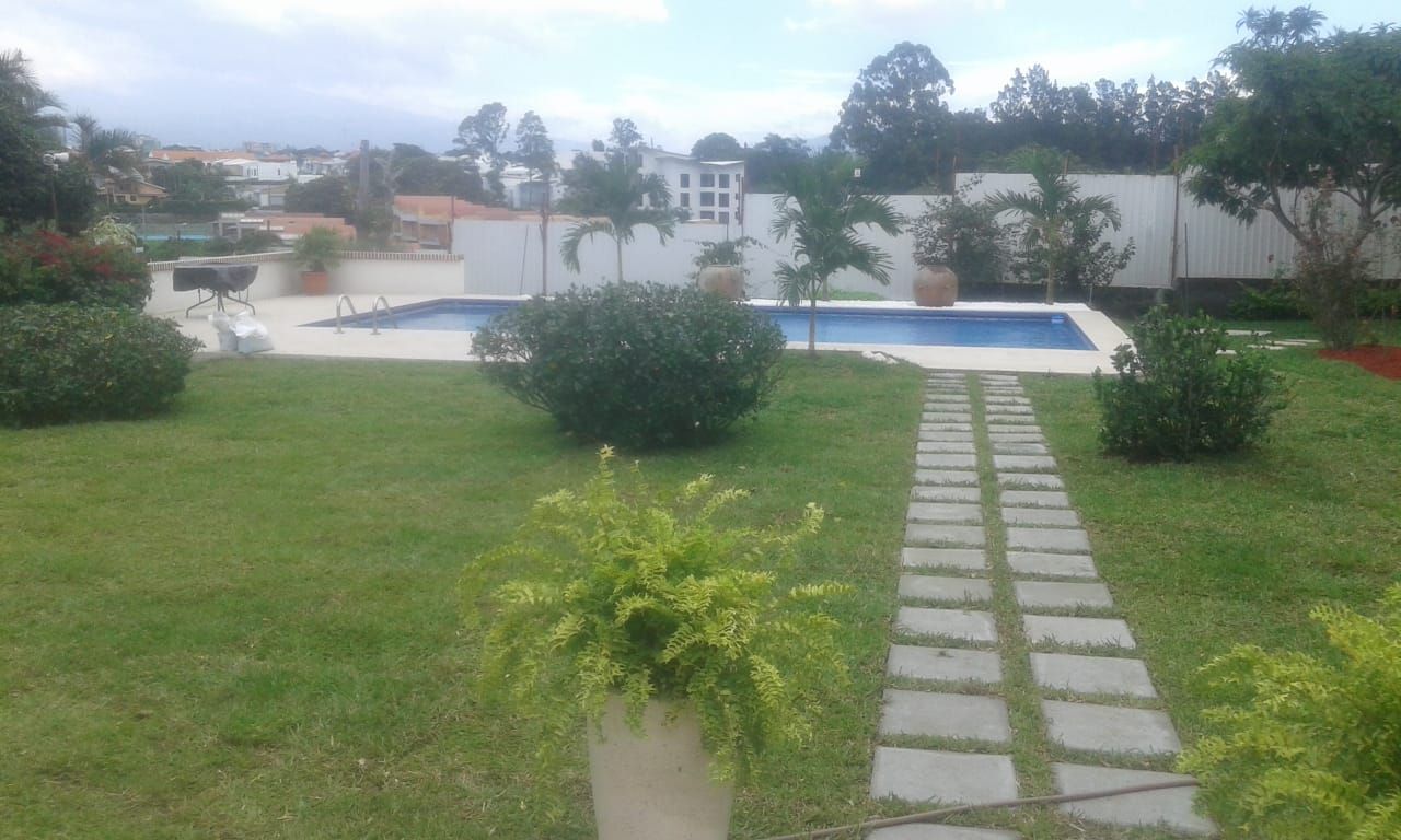 Zona verde con césped y sendero de losetas junto a una piscina