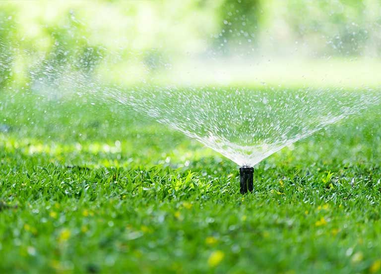 Aspersor de un sistema de riego regando el zacate de un jardín
