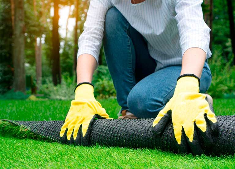 Instalación de un rollo de zacate sintético en un jardín